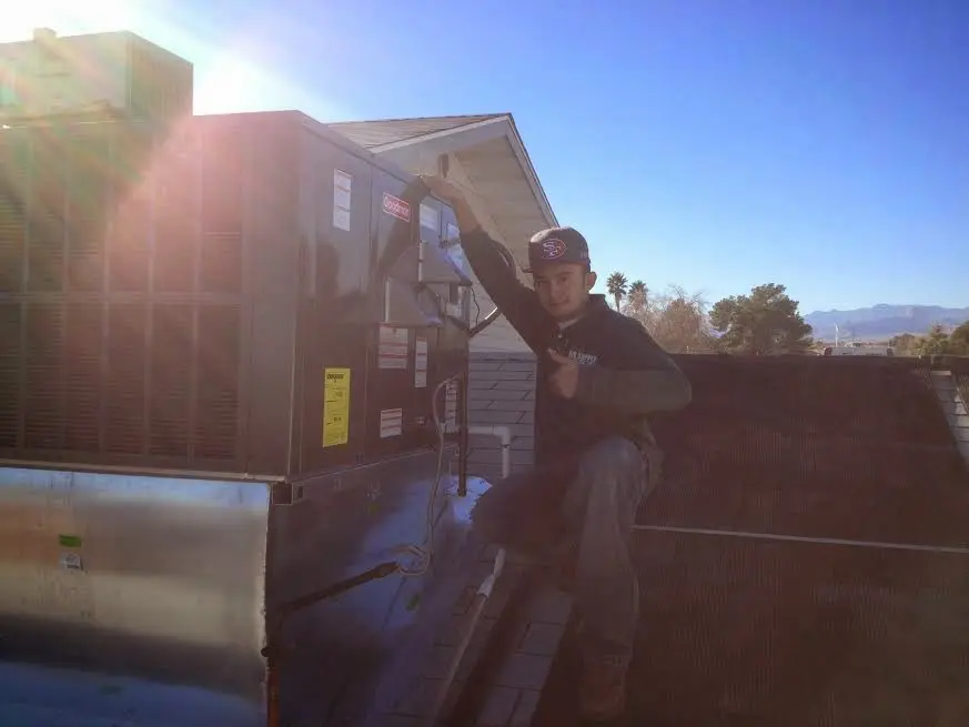 HVAC technician performing Heat Pump Repair on a rooftop unit in Lovejoy
